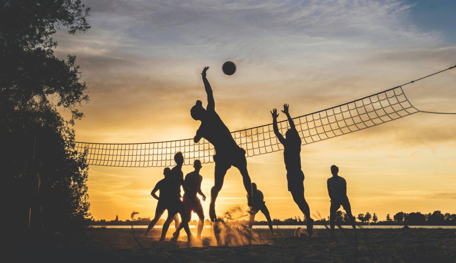 men outdoor volleyball match on beach with beautiful sunset scenes