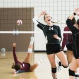 With the best indoor volleyball shoes, girls are happy after the goal of the opponent team on the indoor volleyball court