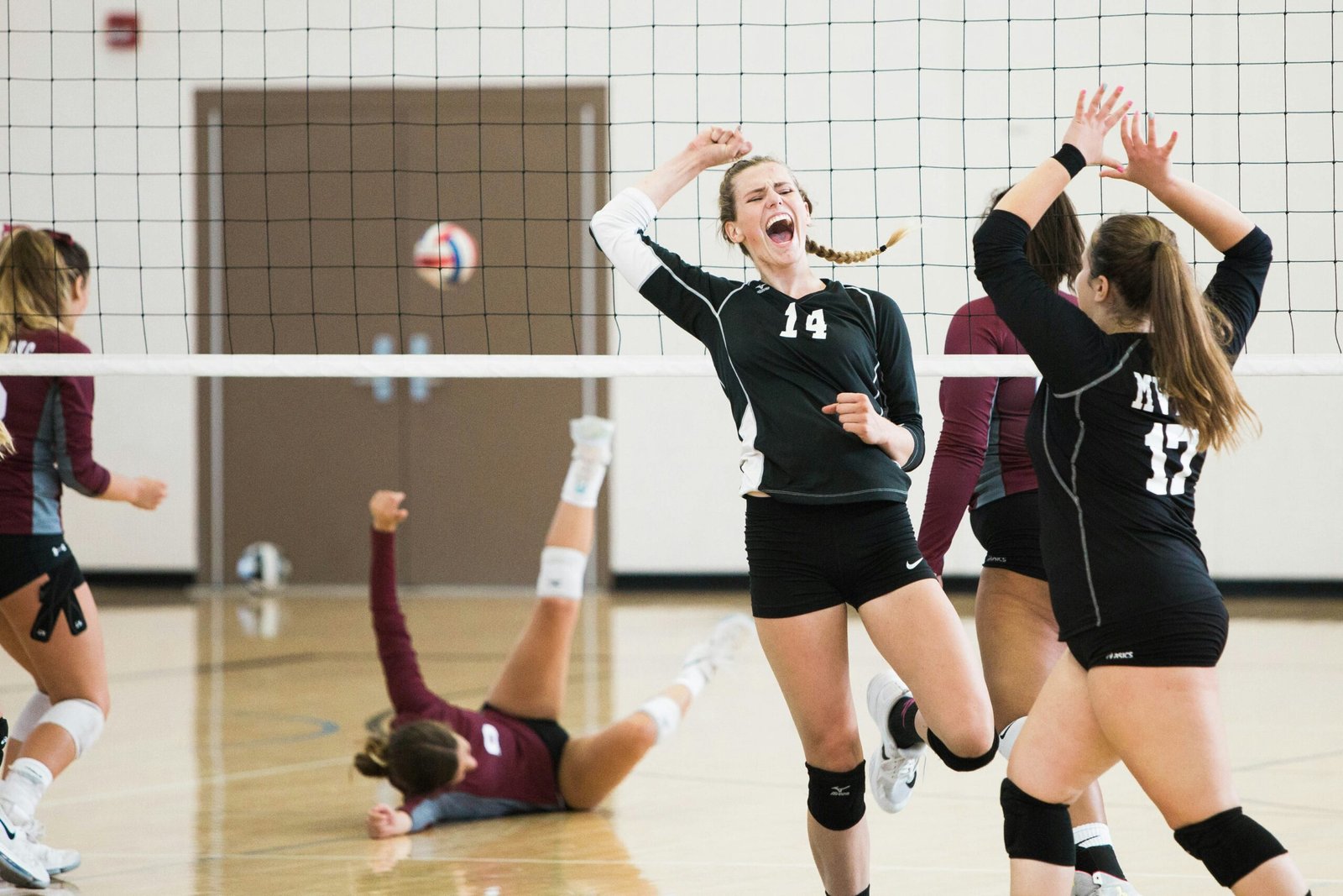 Girls jubilating by winning an indoor volleyball match at the end moment.