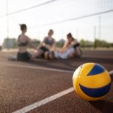 girls wearing volleyball gears in a volleyball court behind the volleyball