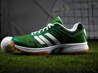 Green sneakers on grass, ideal for grass volleyball, highlighting durability and traction