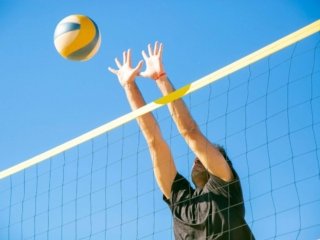 Man pushing a volleyball on an outdoor court, showcasing the durability of volleyball shoes designed for tough surfaces.