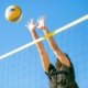 Man pushing a volleyball on an outdoor court, showcasing the durability of volleyball shoes designed for tough surfaces.