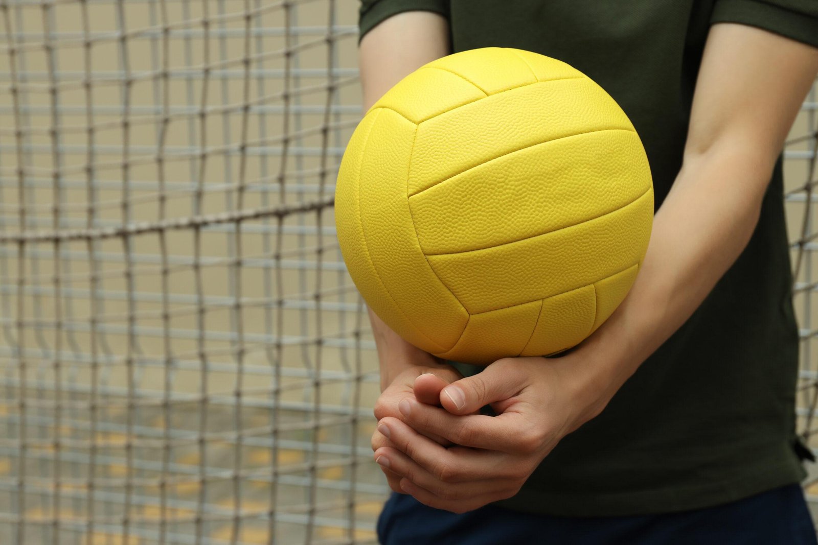 Yellow volleyball held in a player's hand. with mizuno volleyball shoes