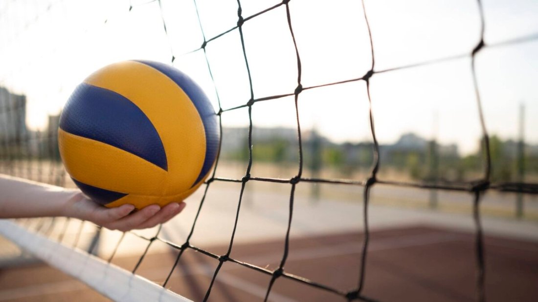 Athlete holding a yellow volleyball on the court, showcasing the best breathable volleyball shoes in action.