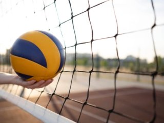 Athlete holding a yellow volleyball on the court, showcasing the best breathable volleyball shoes in action.