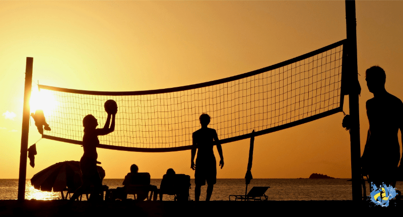 one girl and 2 men's playing volleyball during sunset at beach court