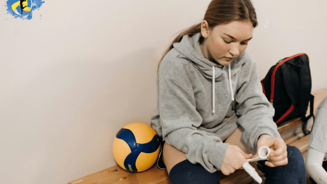 a girl sitting in indoor volleyball court with a volleyball in her side