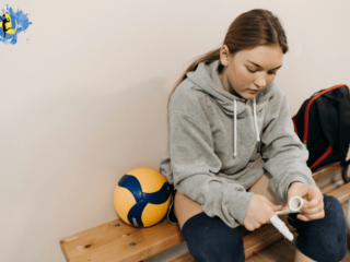 a girl sitting in indoor volleyball court with a volleyball in her side