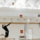 A male volleyball in air to hit a volleyball to other side in the indoor volleyball