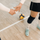 Two women holding hands in indoor volleyball court with a volleyball in background